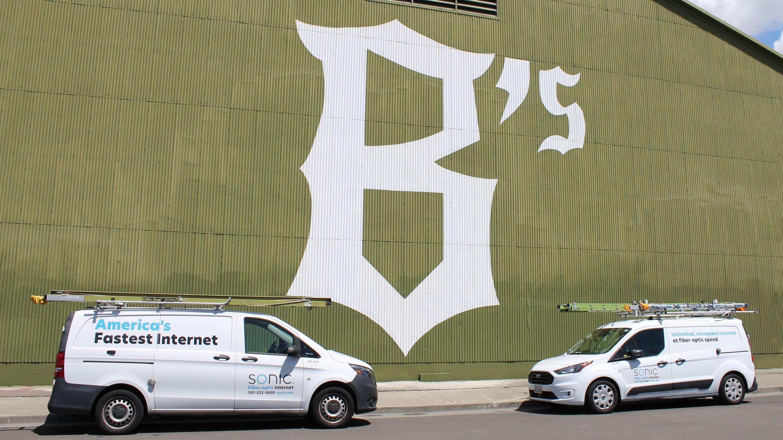 The Oakland Ballers logo painted on a building between two Sonic installer trucks