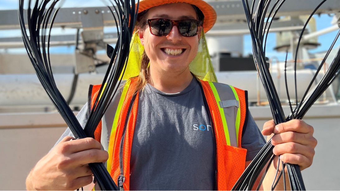 Sonic employee in orange safety vest holding tablet