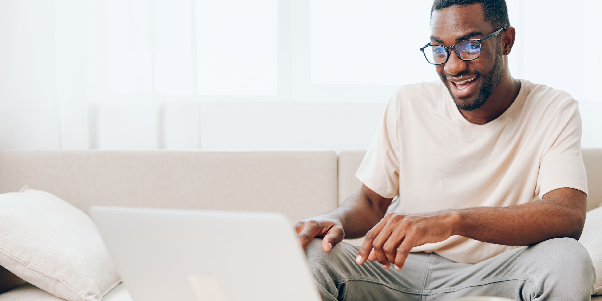 Smiling African American man working on laptop in modern home office.